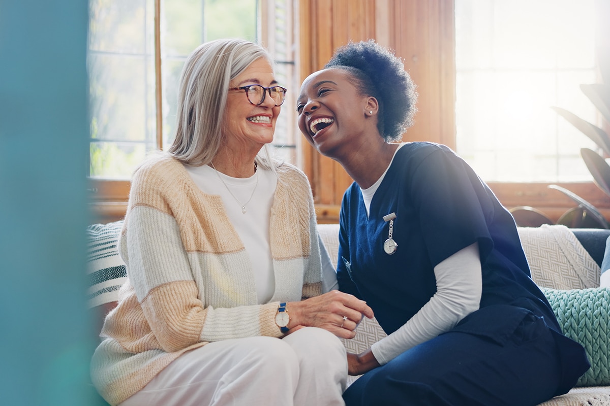 PACS-300x200-hands1 Senior patient, funny or happy caregiver talking for healthcare support at nursing home clinic. Smile, women laughing or nurse speaking of joke to a mature person or woman in a friendly conversation.