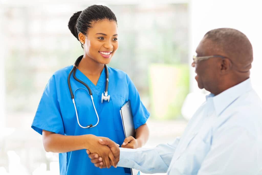 Nurse in blue scrubs shakes hands with an elderly man